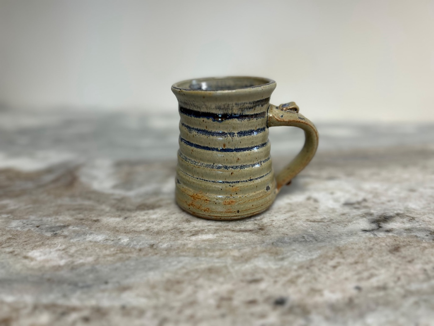 Handmade cream pottery mug with thin navy blue horizontal stripes