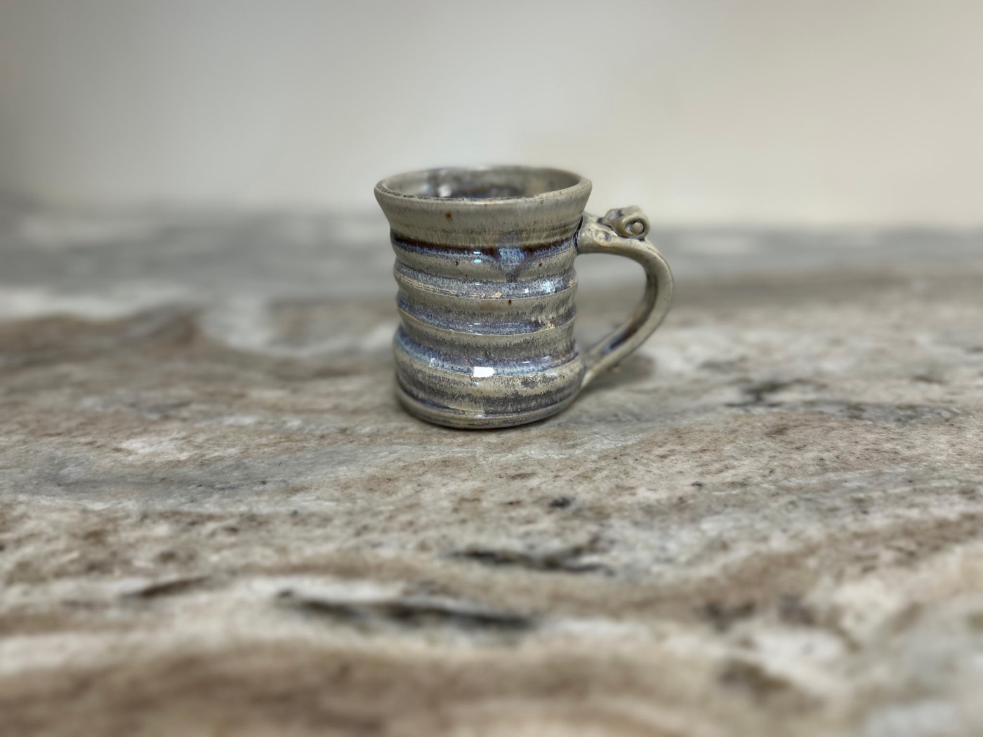 Handmade pottery mug with cream and slate blue wash over carved horizontal bands