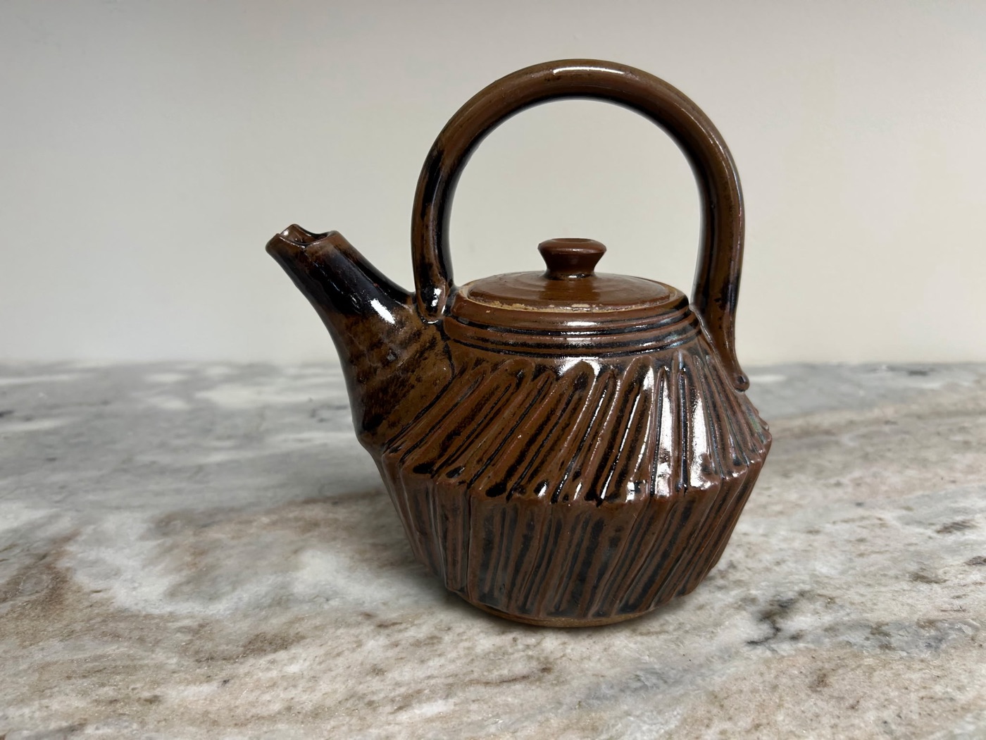 Handmade dark brown stoneware teapot with carved vertical ribs and high arched handle