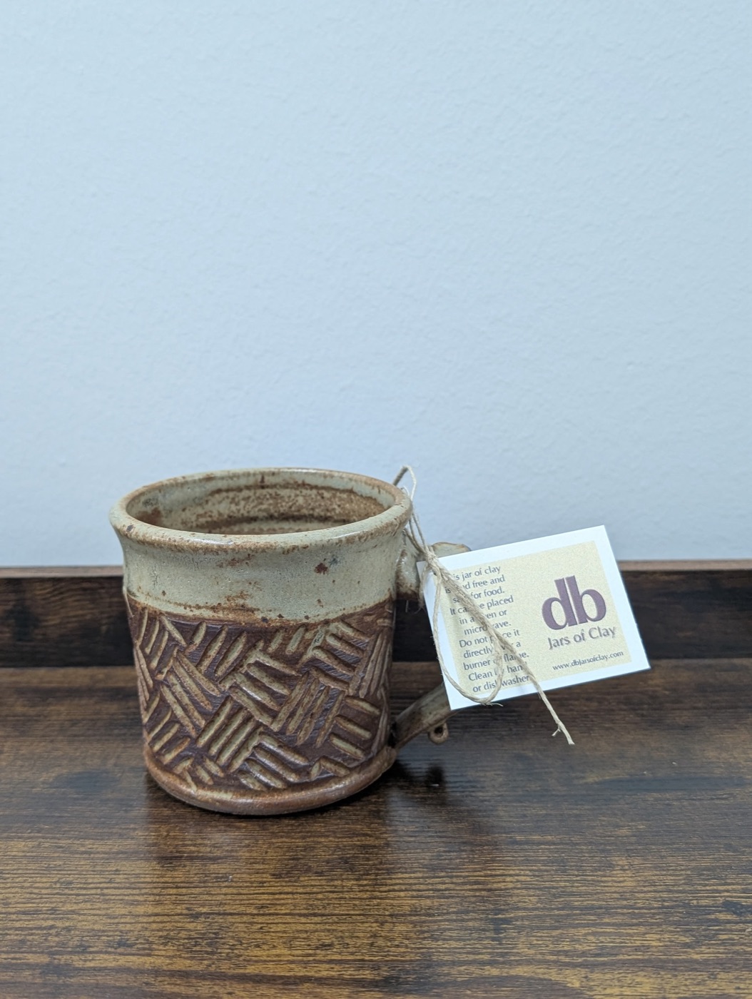 Handmade pottery mug with cream rim and carved basketweave pattern