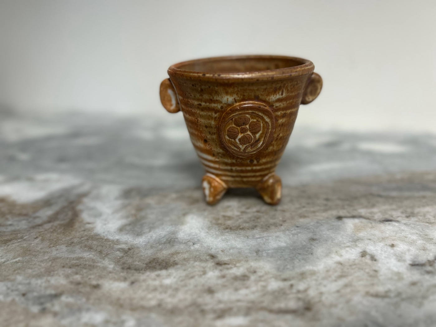 Handmade honey speckled stem bowl with carved floral medallion, side handles, and feet, for cut flowers