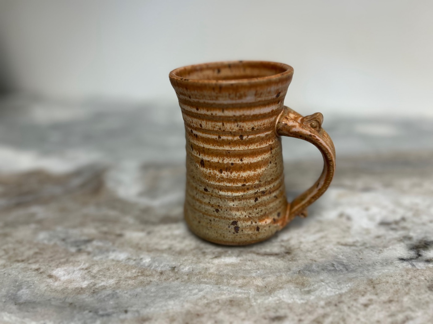 Tall handmade pottery tumbler in warm honey tan with speckled ribbed body
