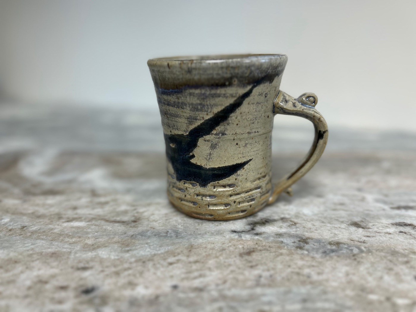 Handmade cream stoneware mug with bold indigo brushstroke and textured base