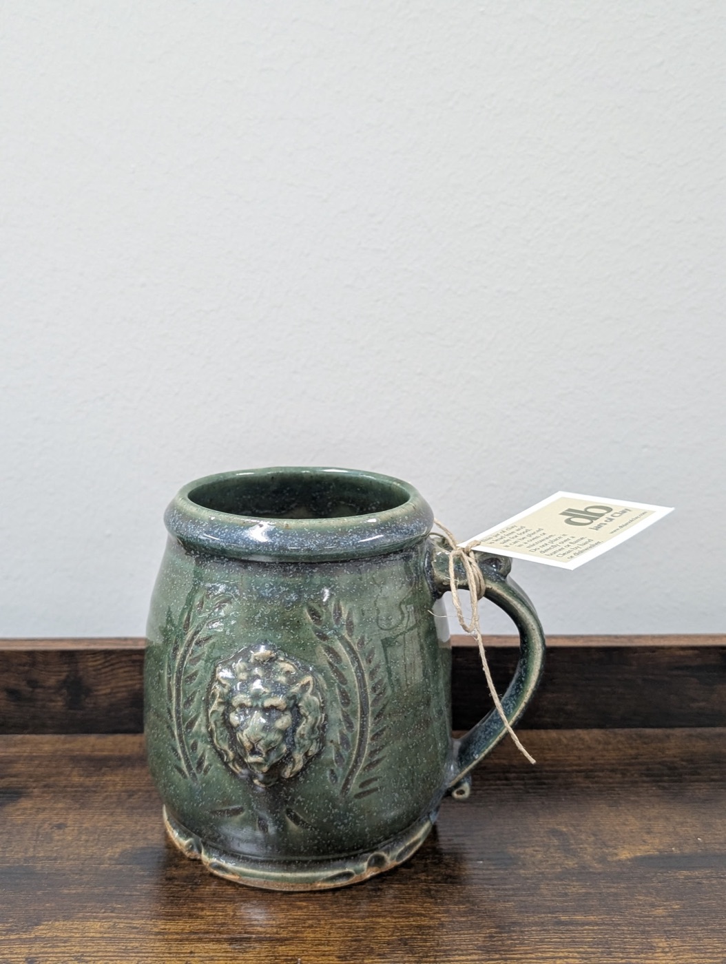 Handmade forest green pottery tankard with raised lion crest and laurel branches
