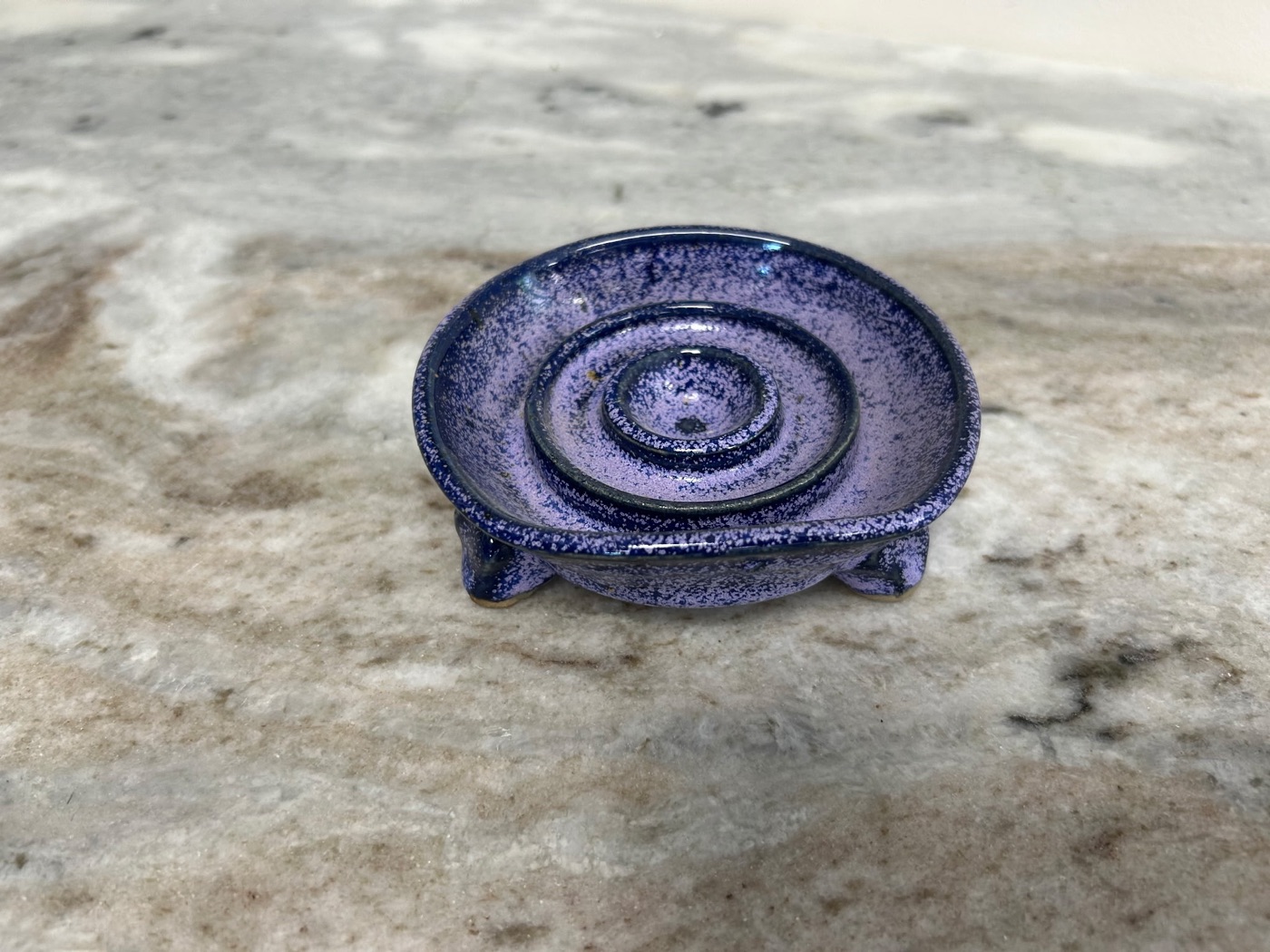 Handmade speckled purple pottery soap dish with concentric drain rings and three feet