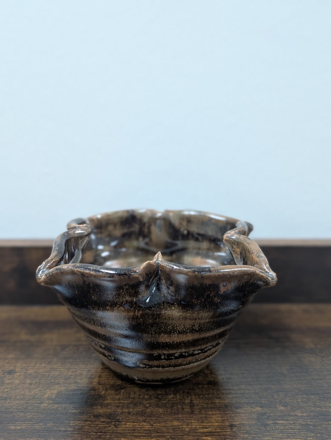 Handmade pottery bowl with dark tortoiseshell glaze and sculptural ruffled rim
