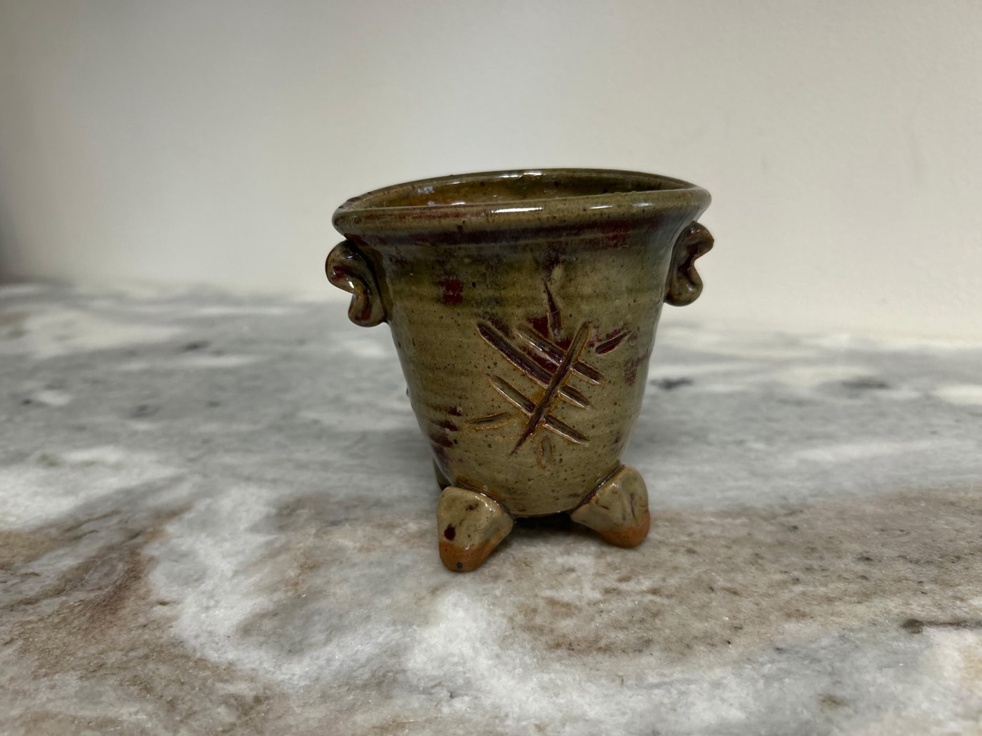 Handmade sage green stem bowl with carved X pattern, three feet, and ear handles, for cut flowers