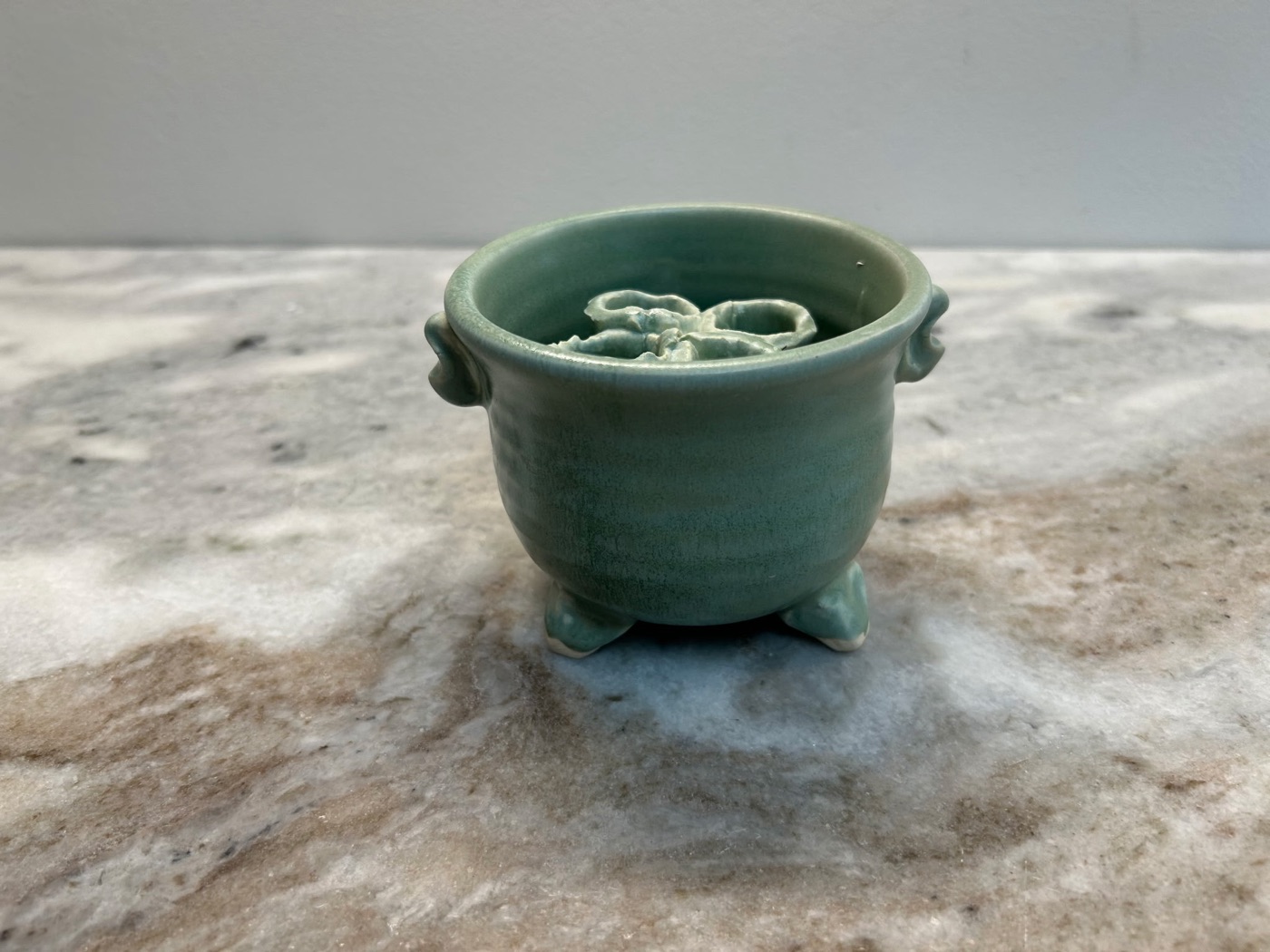 Handmade sage green stem bowl with a built-in flower frog inside to hold cut stems, three feet