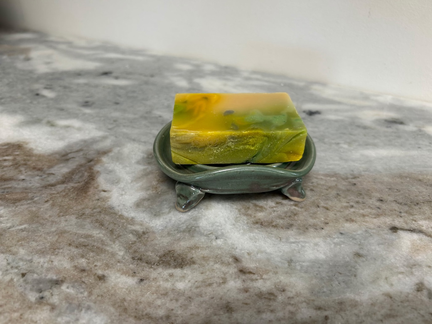 Handmade sage green pottery soap dish with wavy rim and three little feet