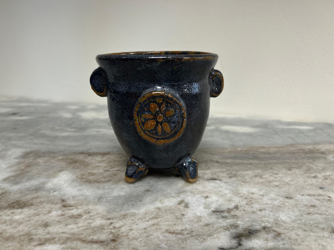 Handmade dark slate stem bowl with raised floral medallion, side handles, and three feet, for cut flowers