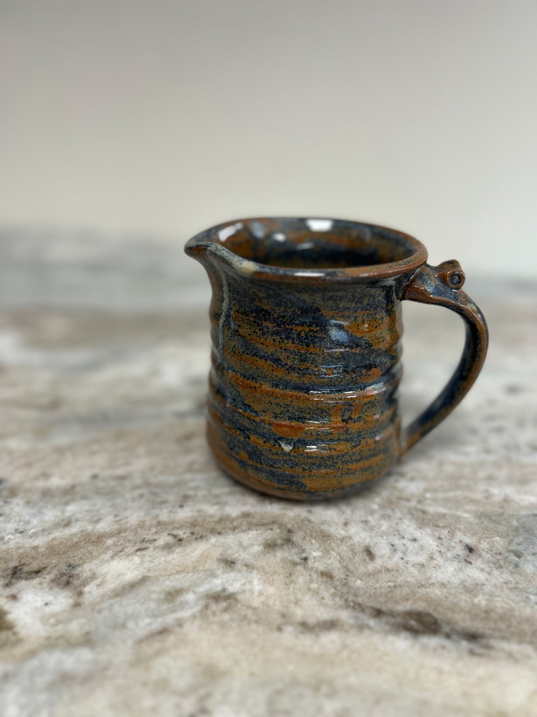 Handmade small pottery pitcher in slate blue and rust marbled glaze with ribbed body