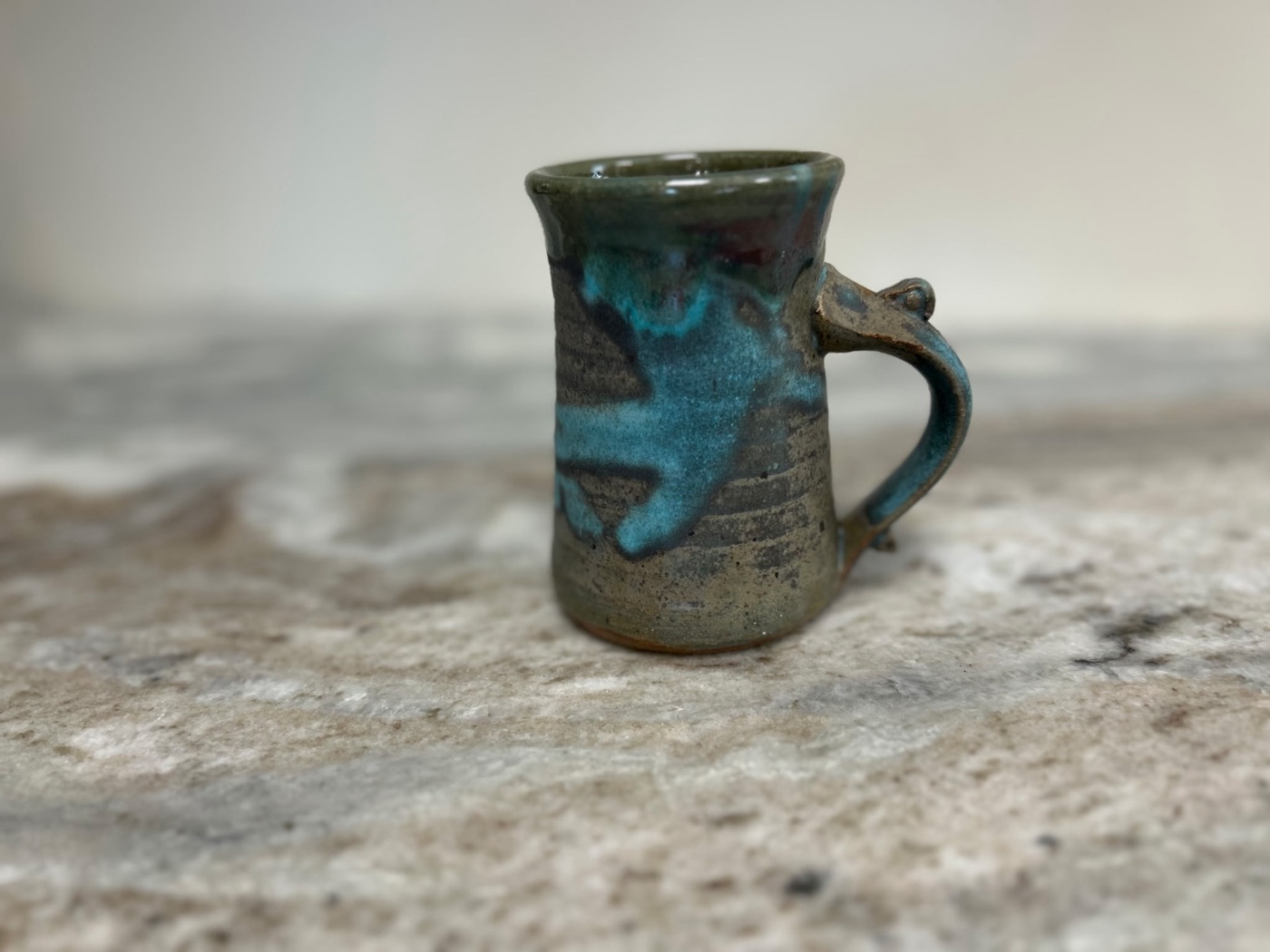 Handmade stoneware mug with turquoise glaze dripping over a slate body