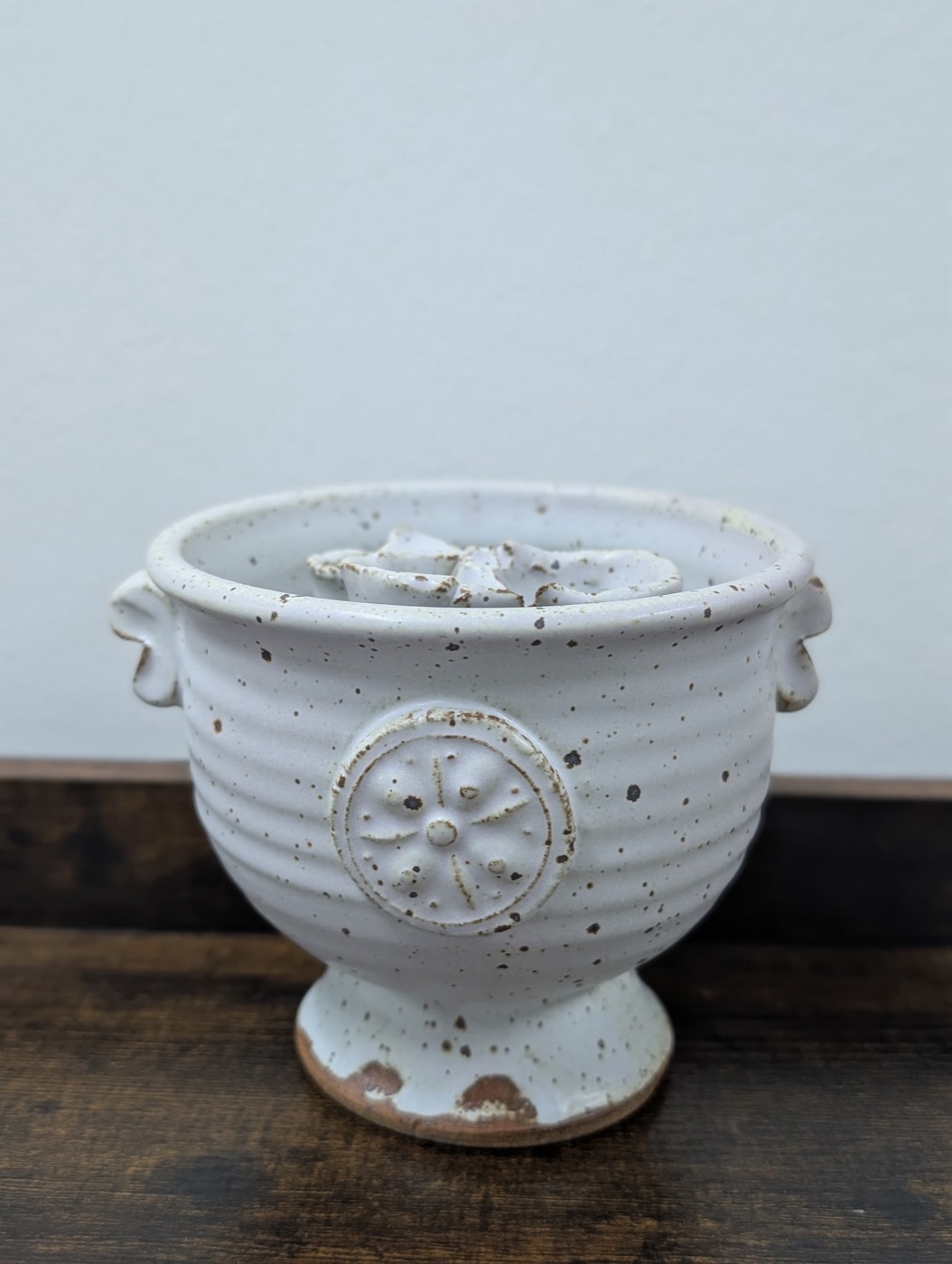 Handmade speckled white pottery pedestal bowl with stamped floral medallion
